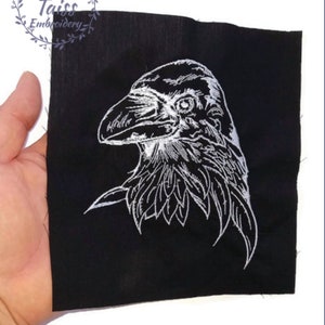 May include: White embroidered raven design on a black fabric patch.