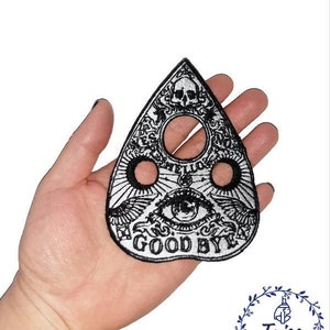 Peut inclure: Patch brodé noir et blanc en forme de planche de sorcière ou de planchette avec les mots "Hello" et "Good Bye" et un motif de crâne et d'œil.