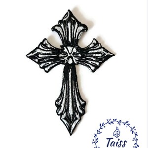 May include: Black and white embroidered iron-on patch of a detailed ornate cross.