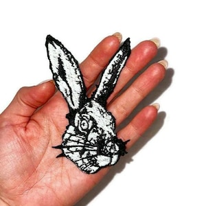 May include: Black and white embroidered iron-on patch of a rabbit's head with a detailed design.