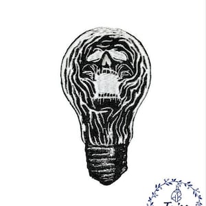 May include: Black and white embroidered patch of a skull inside a light bulb.