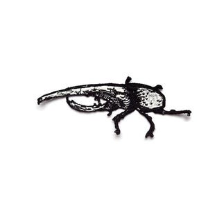 May include: A black and white embroidered patch featuring a detailed insect design. The patch depicts a beetle with intricate detailing on its body and legs. The insect has a prominent horn and is set against a white background.
