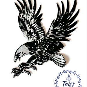 Może przedstawiać: Czarno-biała haftowana naszywka z orłem o rozpostartych skrzydłach w locie. Orzeł jest zwrócony w lewo i ma ostry dziób oraz szpony. Naszywka jest przeznaczona do szycia lub prasowania na ubraniach lub tkaninach.