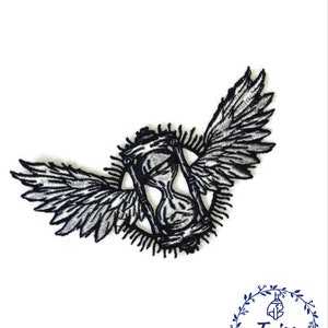 Könnte beinhalten: Schwarz-weiß gestickter Patch eines Sanduhr mit Flügeln. Die Sanduhr ist von einem Kreis aus strahlenden Linien umgeben.