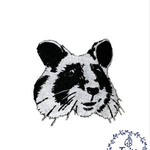 Puede incluir: Diseño bordado en blanco y negro de la cara de un hámster. El hámster tiene una cara blanca y esponjosa con ojos, nariz y bigotes negros.