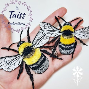 Pu&ograve; includere: Due toppe ricamate di bombi con strisce nere e gialle, ali bianche e zampe nere. I bombi sono su una mano.