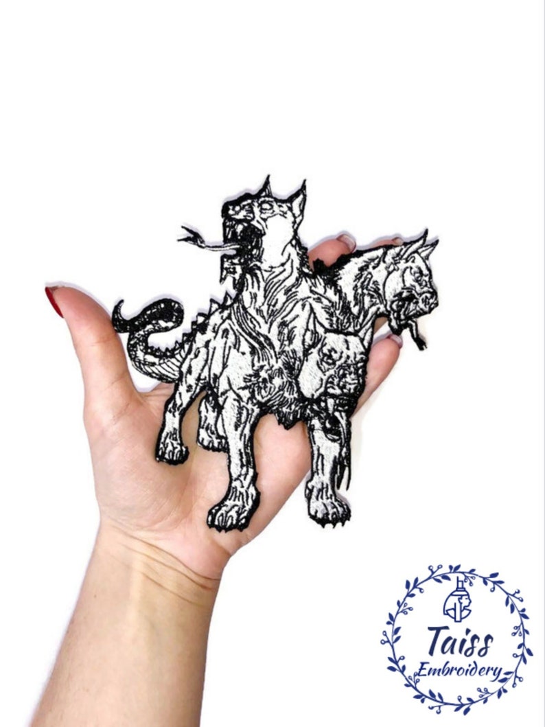 Op de afbeelding: Zwart-wit geborduurde strijk-patch van de driekoppige hond Cerberus uit de Griekse mythologie. De patch is ongeveer 12,7 cm hoog en 10,2 cm breed.