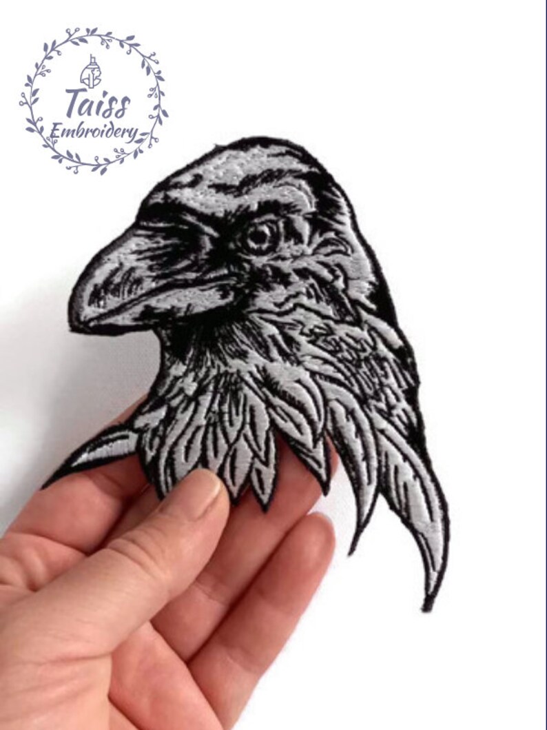 May include: Black and white embroidered iron-on patch of a raven's head with detailed feathers.