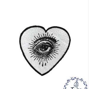 May include: A black and white embroidered patch in the shape of a heart with an eye inside. The eye is surrounded by rays of light.