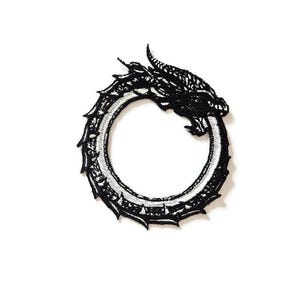 Könnte beinhalten: Schwarz-weißer, gestickter Aufnäher mit einem Ouroboros-Design, einem Drachen, der seinen eigenen Schwanz frisst. Der Drache ist detailliert mit Schuppen und einer strukturierten Oberfläche. Der Aufnäher ist kreisförmig.