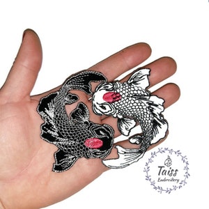 Peut inclure: Deux patchs brodés thermocollants de poissons koï noirs et blancs en forme de yin yang. Les poissons ont des accents rouges sur la bouche.