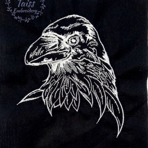 May include: White embroidered design of a raven's head on a black fabric background.