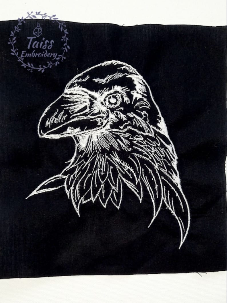 May include: White embroidered design of a raven's head on a black fabric background.