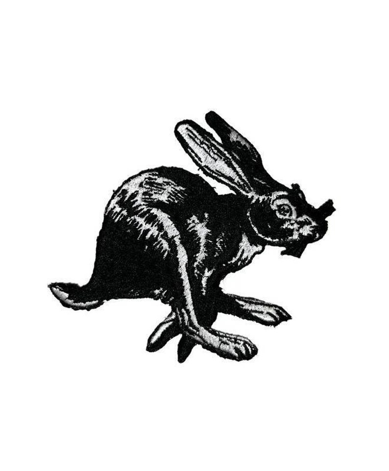 May include: Black and white embroidered patch of a rabbit running. The rabbit is facing the right side of the image.
