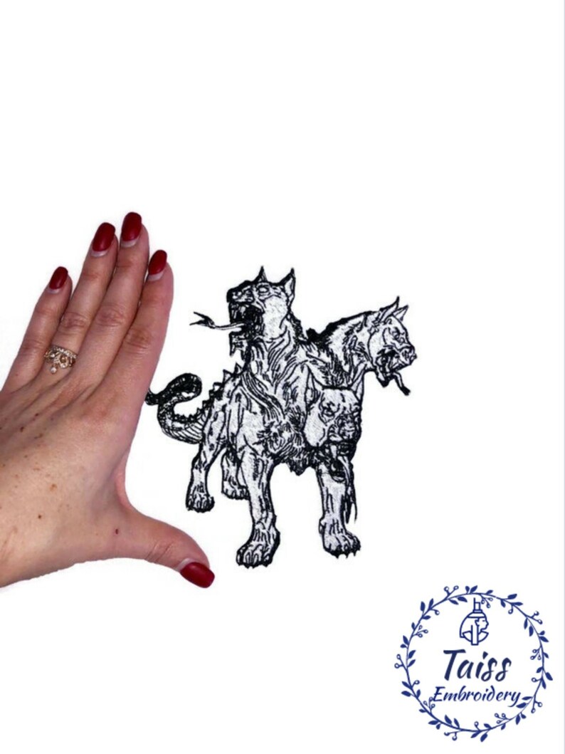 Op de afbeelding: Zwart-witte geborduurde patch van een driekoppige hond, Cerberus, met een hand voor schaal.