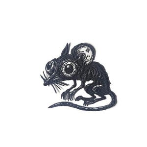 Close-up of a black and white embroidered rat patch featuring oversized eyes and visible rib cage, mystical dark academia aesthetic on a clean background.