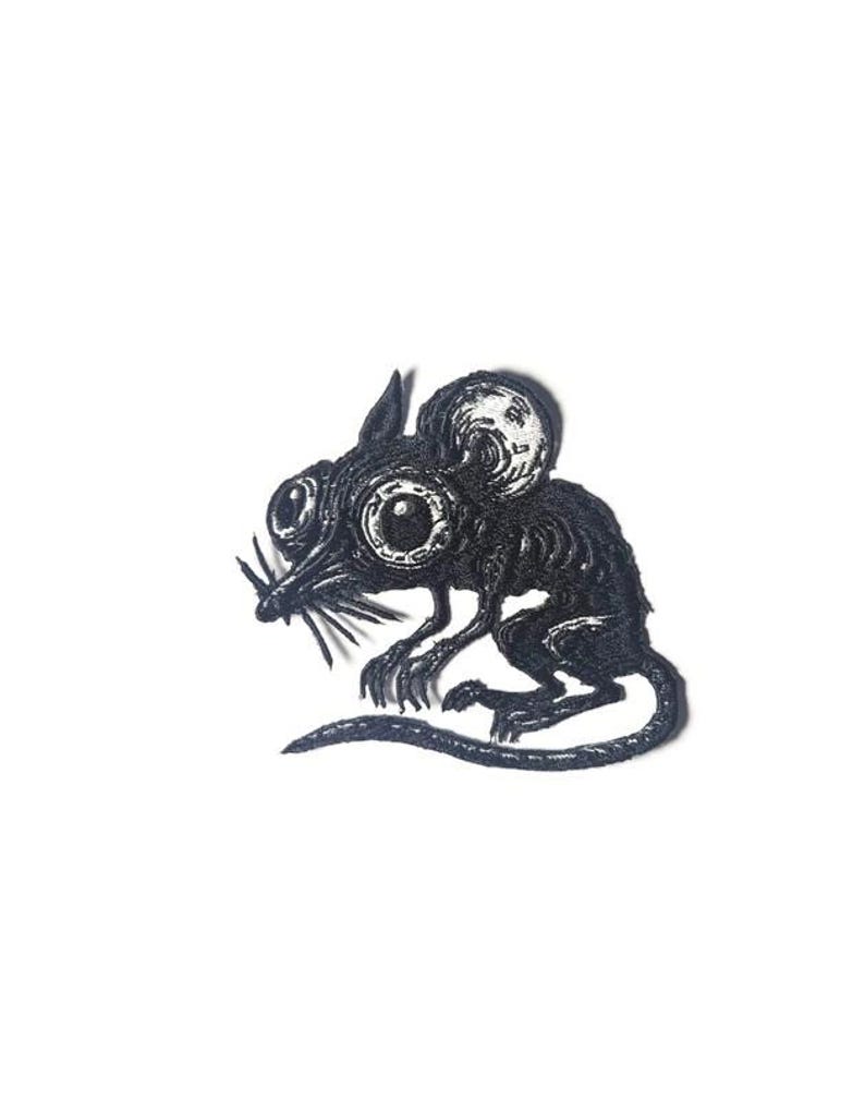Close-up of a black and white embroidered rat patch featuring oversized eyes and visible rib cage, mystical dark academia aesthetic on a clean background.