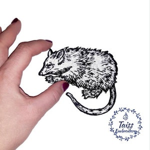 May include: Black and white embroidered iron-on patch of a possum curled up sleeping. The patch is on a white background.