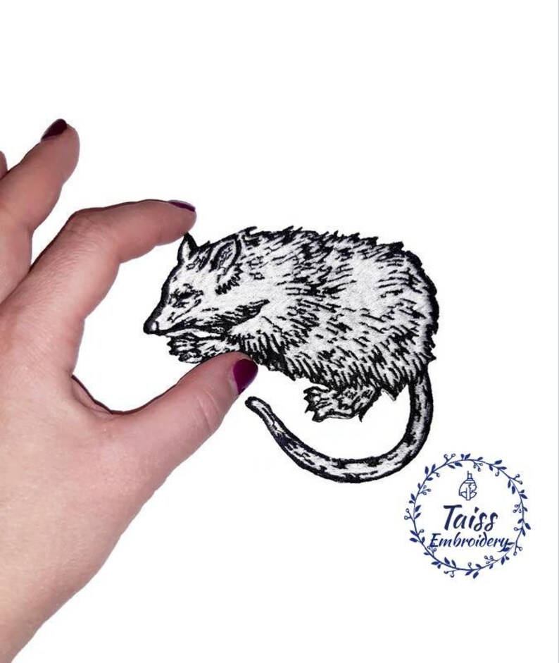 May include: Black and white embroidered iron-on patch of a possum curled up sleeping. The patch is on a white background.