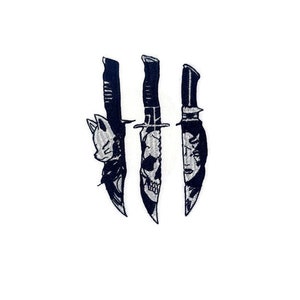 May include: Three black knives with different designs on the blades. The knives are arranged vertically in a row.