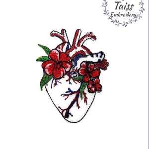 Puede incluir: Parche bordado de un corazón anatómico blanco con flores rojas y hojas verdes. El corazón tiene venas y arterias azules. El parche es para coser o planchar sobre tela.