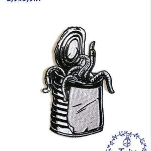 Pode incluir: Etiqueta bordada em preto e branco de uma criatura com tentáculos numa lata. A etiqueta mede 3,9 x 5,9 polegadas.