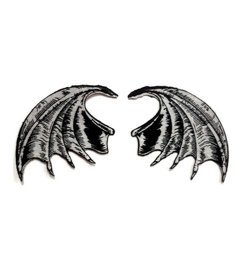 K&ouml;nnte beinhalten: Ein Paar schwarze und silberne gestickte Fl&uuml;gel mit einem detaillierten Design. Die Fl&uuml;gel sind getrennt und einander zugewandt.