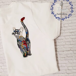 May include: White t-shirt with a colorful embroidered cat design. The cat is facing away from the viewer and has a long tail. The embroidery is detailed and intricate, with a variety of colors and patterns.