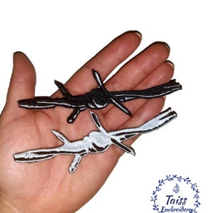 May include: Two iron-on patches of barbed wire, one black and one white, on a hand. The patches are about 3 inches long.
