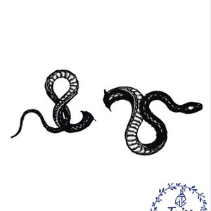 May include: Two black embroidered snake designs. The snakes are curled in a circle and a 'S' shape. The embroidery is detailed and intricate.