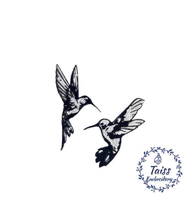 K&ouml;nnte beinhalten: Zwei schwarze und wei&szlig;e Kolibri-Silhouetten im Flug, die sich gegen&uuml;berstehen. Das Bild ist vor einem wei&szlig;en Hintergrund. Der Text "Taiss Embroidery" befindet sich in einem Kreis mit einem floralen Design.