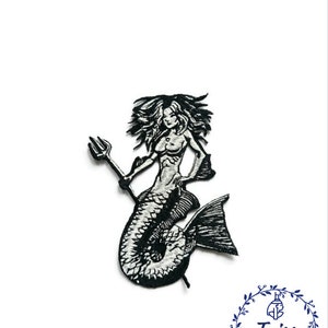 May include: Black and white embroidered patch of a mermaid holding a trident. The mermaid has long flowing hair and a fish tail.