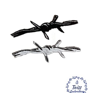 May include: Two black and white barbed wire patches. The patches are embroidered and have a rough, textured look.