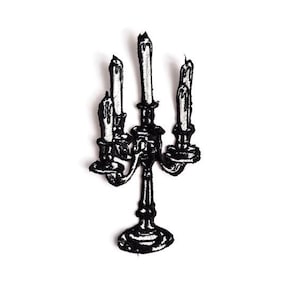 May include: Black and white embroidered patch of a candelabra with three lit candles. The candles have melted wax details. The candelabra has a decorative base and arms, and is set against a white background.