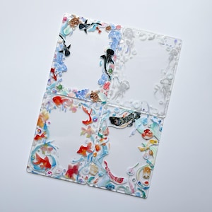May include: Four clear acrylic panels with decorative borders featuring aquatic life. The borders include colorful fish, sea turtles, and jellyfish. The panels are arranged on a white surface, creating a vibrant and artistic display.