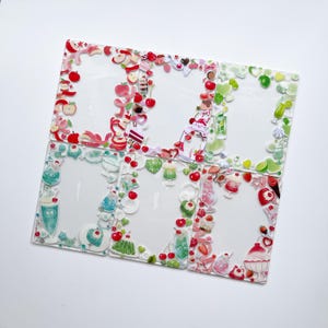 May include: A set of six clear, rectangular stickers with decorative borders. Each border features a different assortment of colourful, cartoonish fruit and dessert illustrations, including apples, cherries, and ice cream.