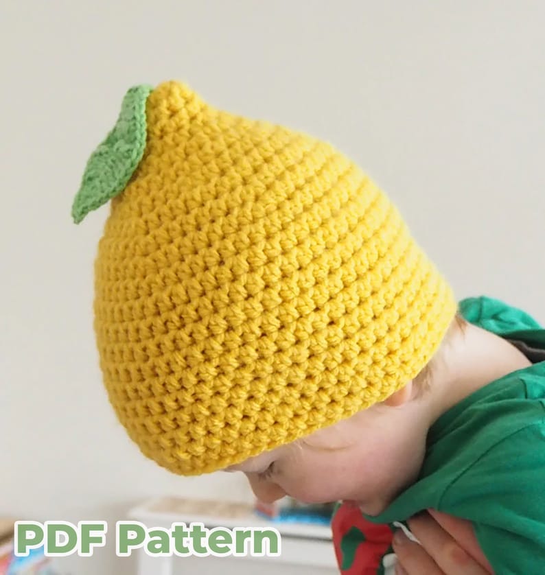 Puede incluir: Un gorro de punto de ganchillo amarillo en forma de lim&oacute;n con una hoja verde en la parte superior.  Patr&oacute;n PDF.