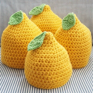 Puede incluir: Tres almohadas de punto de crochet con forma de lim&oacute;n y hojas verdes. Las almohadas son amarillas y tienen una superficie texturizada.