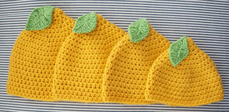 Puede incluir: Cuatro gorros de punto de lim&oacute;n en diferentes tama&ntilde;os, con hojas de fieltro verde en la parte superior. Los gorros son amarillos y tienen un patr&oacute;n de punto texturizado.
