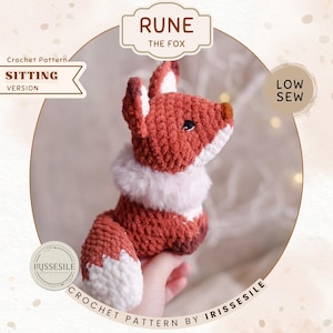 May include: A crocheted fox toy in a sitting position, featuring a reddish-brown body with white accents on the chest and legs. The fox has a white fluffy collar and a brown nose. The text "RUNE THE FOX" and "CROCHET PATTERN BY IRISSESILE" are visible.