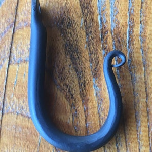 May include: A black metal hook with a curved design. The hook is made of wrought iron and has a rustic finish.