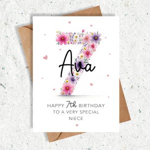 May include: A birthday card with a floral number seven design. The number is filled with pink and purple flowers, with the name "Ava" in black script. The card reads "Happy 7th Birthday to a very special niece."