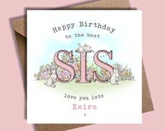 Può includere: Un biglietto di compleanno rosa con la parola "SIS" in grandi lettere rosa circondate da coniglietti bianchi e fiori. Il biglietto dice "Happy Birthday to the best SIS love you lots Keira x".