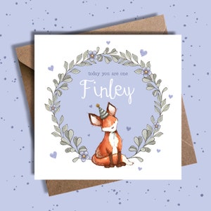 May include: A purple and white birthday card with a fox wearing a party hat and a wreath of leaves and flowers. The card says "today you are one Finley".