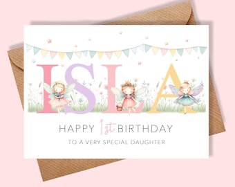May include: A birthday card with the name "Isla" in large, colorful letters, featuring illustrations of fairies. The card reads "Happy 1st Birthday" and "To a very special daughter" on a white background, with a brown envelope.