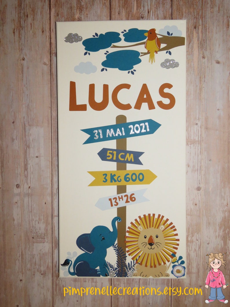 K&ouml;nnte beinhalten: Ein beigefarbener Wachstums-Leinwand mit einem braunen Holzpfosten und blauen, gelben und wei&szlig;en Richtungsschildern. Die Schilder zeigen den Namen Lucas, das Datum 31 Mai 2021, 51 cm, 3 kg 600 und 13h26. Die Grafik zeigt einen blauen Elefanten und einen gelben L&ouml;wen mit orangefarbener M&auml;hne.