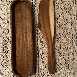 May include: A wooden serving tray and a matching wooden scoop. The tray is rectangular and has a slight curve to it. The scoop is long and narrow with a rounded end.