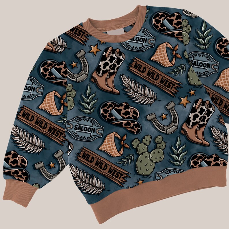 May include: A blue sweatshirt with a repeating pattern of cowboy boots, hats, cacti, feathers, horseshoes, and saloon signs. The text "WILD WILD WEST" is repeated throughout the pattern.
