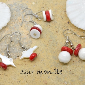 Peut inclure: Trois paires de boucles d'oreilles avec des perles de coquillage blanches et rouges. Les boucles d'oreilles sont sur une surface beige avec des coquillages blancs.