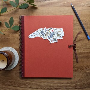 The Birds of North Carolina sticker is shown on a red notebook